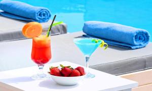 a glass of orange juice next to a bowl of fruit at Elounda Garden Suites Heated Pool in Elounda