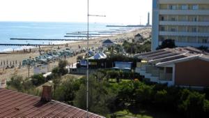Blick auf einen Strand mit einem Gebäude und das Meer in der Unterkunft Hotel Condor in Lido di Jesolo