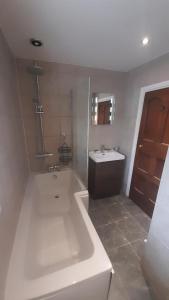 a white bathroom with a tub and a sink at Ty Gwyn Cottage & Hot Tub in Betws-y-coed