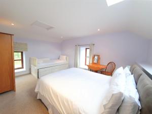 1 dormitorio con cama blanca y escritorio en Fodol Cottages, en Menai Bridge