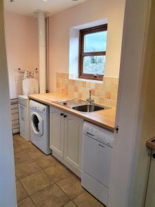 a kitchen with a sink and a washing machine at Fodol Cottages in Menai Bridge