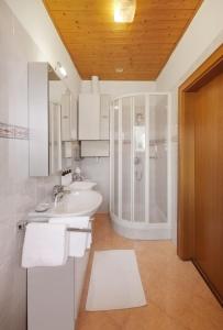 een badkamer met een wastafel en een douche bij Ferienwohnung im Herzen Kalterns mit einer Terasse zum verlieben in Caldaro