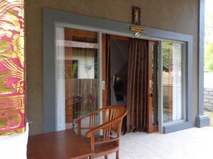 a table and a chair in front of a glass door at Pondok Dhevika and Warung in Pemuteran