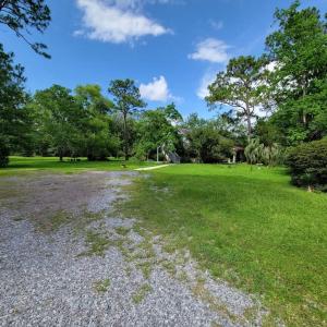 a gravel road in a field with trees and grass at Bohemian Dreamin in Mobile