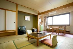 a living room with a table and chairs and a tv at Toya Kanko Hotel in Lake Toya