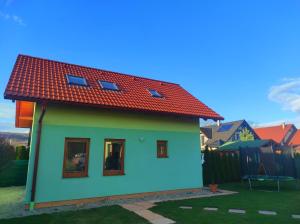 una pequeña casa con techo rojo en Green cottage Besenova, en Bešeňová