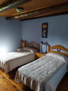 2 Betten in einem Zimmer mit blauen Wänden und Holzböden in der Unterkunft Casa Cebollero Autural in Fraginal