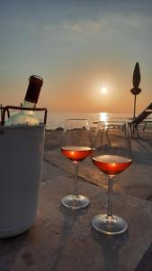 two glasses of wine sitting on a table near the ocean at Apartma Coccolo in Zambratija +11 photos