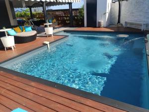 una piscina con terraza de madera y piscina en ZANNANNA F1 de charme tout équipé Le Moule avec piscine, en Le Moule