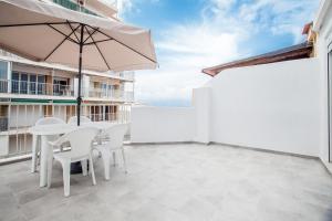 een patio met een tafel en stoelen en een parasol bij Ático con espectacular terraza y vistas al mar in El Perelló
