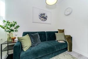 a green couch in a living room with a clock on the wall at Tallinn City Harbour Apartments in Tallinn