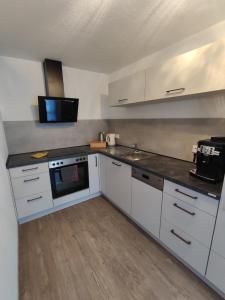 a kitchen with white cabinets and a stove top oven at Ferienwohnung Im Stiffje in Schalkenmehren