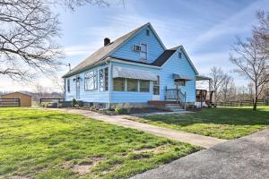 a blue house sitting on top of a lush green field at Charming East Bernstadt Retreat Less Than 6 Acre Farm! in East Bernstadt
