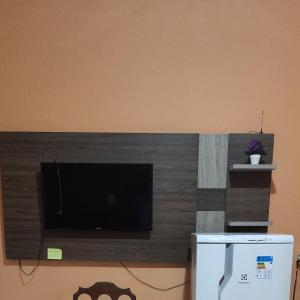 einen Flachbild-TV an einer Wand neben einem Kühlschrank in der Unterkunft CARABAO Hostel in Soure
