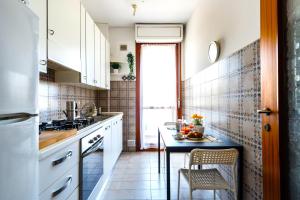 uma cozinha com armários brancos e uma pequena mesa em Hostly - Family Home Cisanello em Pisa