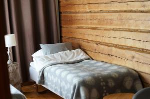 a bed in a room with a wooden wall at Bear Manor B&B in Kannonkoski