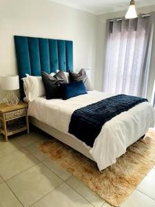 Schlafzimmer mit einem großen Bett mit blauem Kopfteil in der Unterkunft The Blyde -Ender137 in Pretoria
