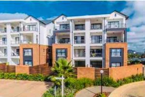 a large apartment building with a palm tree in front of it at The Blyde -Ender137 in Pretoria