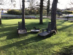 two benches sitting in the grass next to trees at La Tour Des Quatre Chemins in Gramat