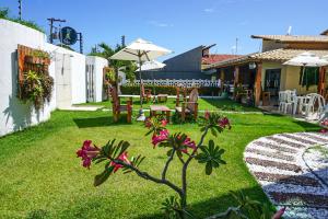 um jardim com uma mesa e cadeiras e um guarda-sol em Pousada Paris na Praia do Francês