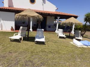 quattro sedie a sdraio e ombrelloni davanti a una casa di Monte Geralda a Cercal