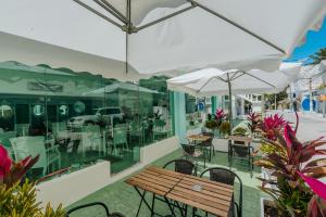 eine Terrasse mit einer Holzbank, Tischen und Sonnenschirmen in der Unterkunft Green Coast Beach Hotel in Punta Cana