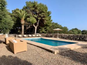 una piscina en un patio con sillas y sombrilla en Islanders Menorca Country Club, en Son Carrio