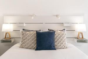 a bed with three pillows and two lamps at Consolação Supertubos Beach Apartment in Consolação