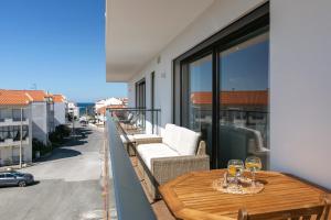 a balcony with a table and two glasses of wine at Consolação Supertubos Beach Apartment in Consolação