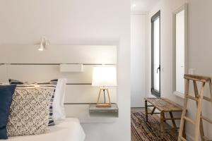 a bedroom with white walls and a bed with a lamp at Consolação Supertubos Beach Apartment in Consolação