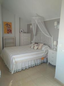 a white bedroom with a bed with a canopy at Ático Dúplex con vistas in Murcia