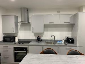 una cocina con armarios blancos y una mesa con sillas. en Tanllan Apartment, en Callander