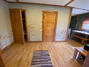 a room with wooden floors and doors and a table at Camping Bušas in Saulkrasti