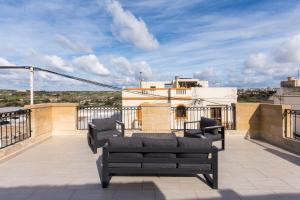 a balcony with two couches on top of a building at Rabat Farmhouse with pool and cave in Għajn Qajjied