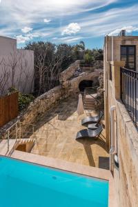 a patio with a blue swimming pool on a building at Rabat Farmhouse with pool and cave in Għajn Qajjied