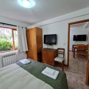 Un dormitorio con una cama, un televisor y una silla. en Golondrinas - Andarlibre, en San Martín de los Andes
