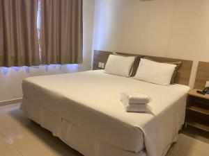 Schlafzimmer mit einem Bett mit weißer Bettwäsche und einem Fenster in der Unterkunft Hotel Palace Santarém Brasil in Santarém