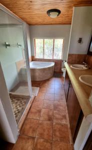 a bathroom with a tub and two sinks and a shower at Boabab Lodge in Mabula
