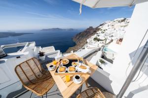 stół z jedzeniem na balkonie z widokiem na ocean w obiekcie Smaro Studios w mieście Firostefani