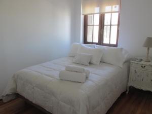 Cama blanca con almohadas blancas y ventana en Apartamentos en el palacio salvo, en Montevideo