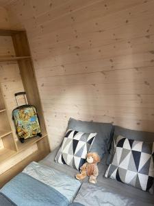 un osito de peluche sentado en una cama en una cabaña en Oslo N°29 Domek Letniskowy, en Borsk