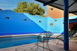 une piscine avec des chaises à côté d'un mur bleu dans l'établissement Hotel Costamar, Puerto Escondido, à Puerto Escondido