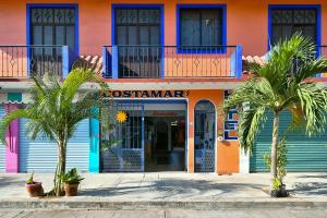 un bâtiment coloré avec des palmiers devant lui dans l'établissement Hotel Costamar, Puerto Escondido, à Puerto Escondido