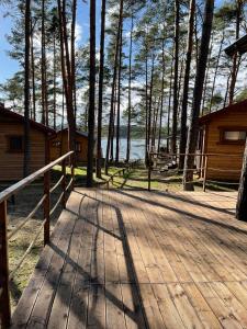 un paseo marítimo de madera que conduce a una cabaña con árboles en Oslo N°29 Domek Letniskowy, en Borsk