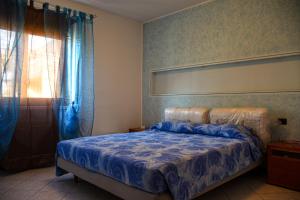 a bedroom with a bed with a blue comforter and a window at Casa Rosetta in Pescantina