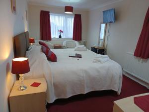 a bedroom with a large white bed with red curtains at Palm Court in Weymouth