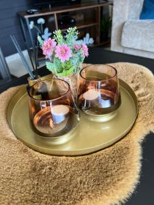 einen Tisch mit drei Gläsern auf einem Teller mit Blumen in der Unterkunft Vakantiehuis Gertrude in Middelkerke