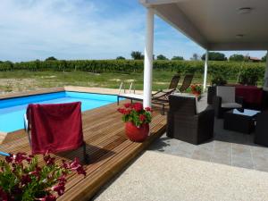 una terraza de madera con sillas y una piscina en Gîte Les Vignes en Cravencères