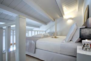 una camera da letto bianca con un grande letto bianco e pareti bianche di Corfu Centro Storico flat a Città di Corfù