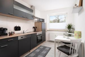 eine Küche mit schwarzen Schränken und einem weißen Tisch in der Unterkunft Aparte - Washer & Dryer - Kitchen & Parking - Smart-TV in Sarstedt